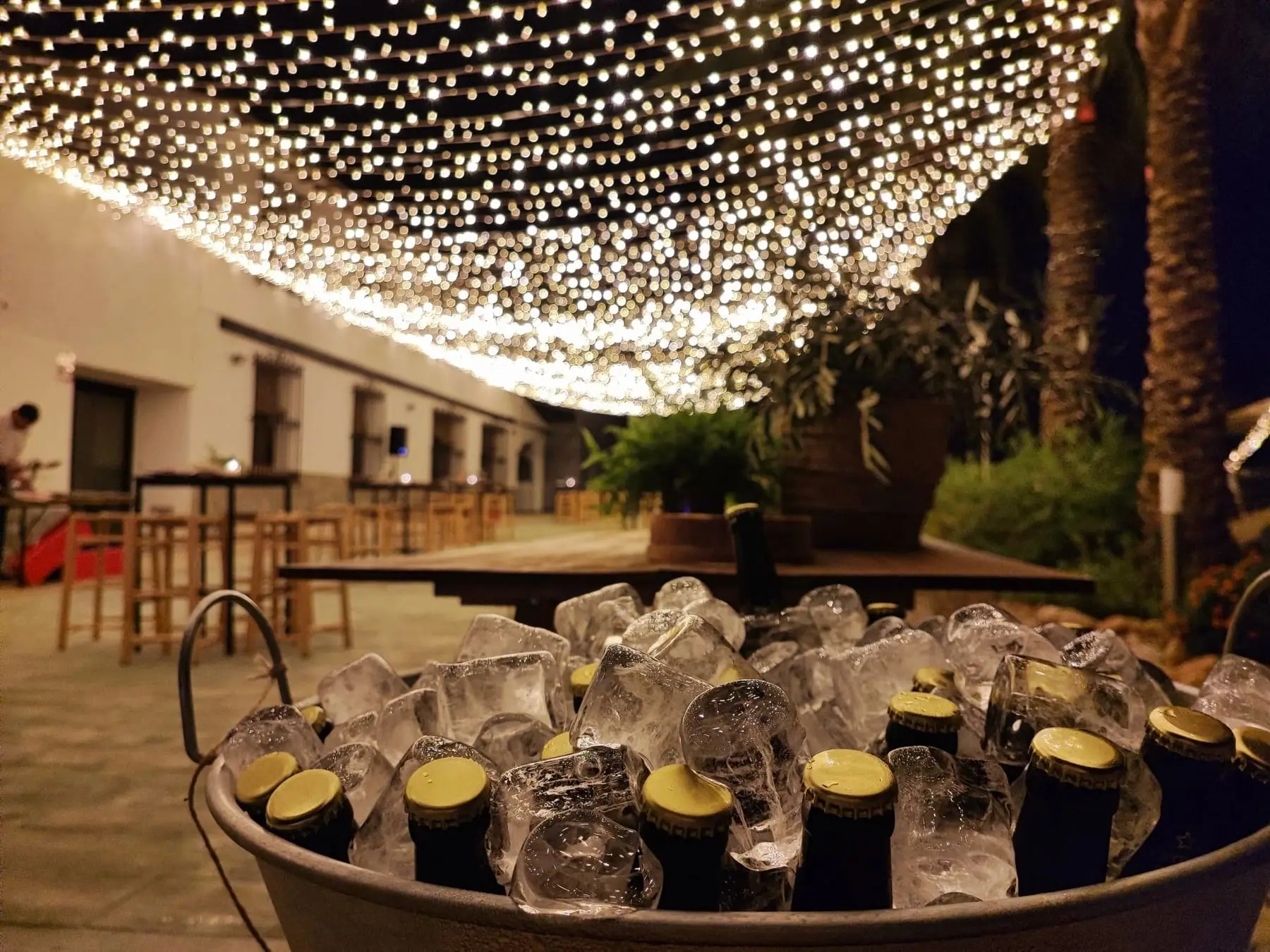 Bottles chilling in a tub of ice under a canopy of lights, the terrace and bar beyond
